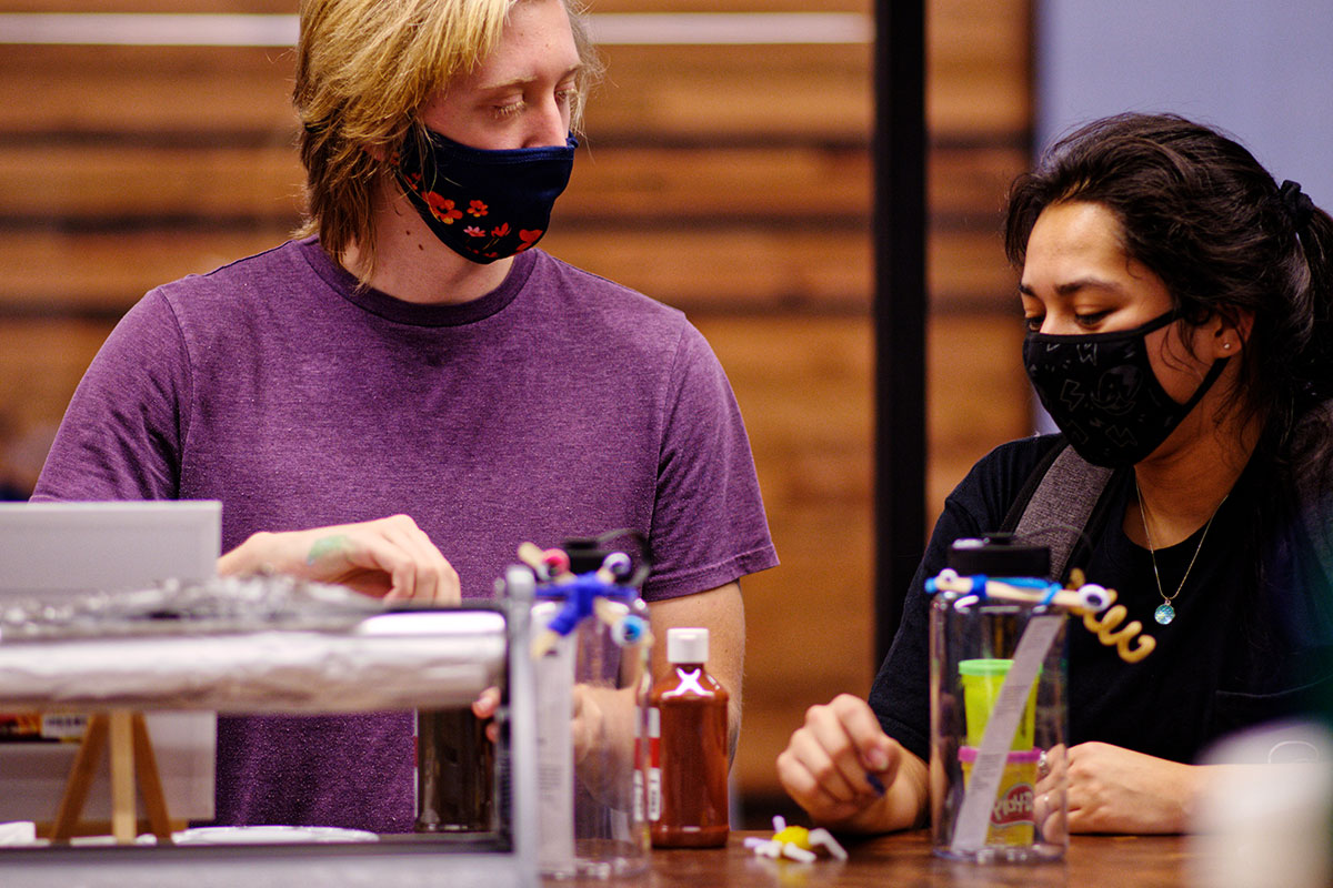 Two masked Emory community members work at a table