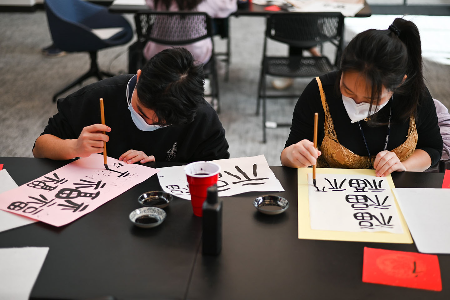 Two young people work on calligraphy
