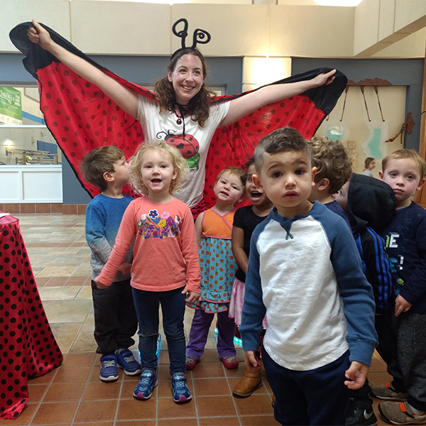 woman dressed in lady bug costume with young children around her