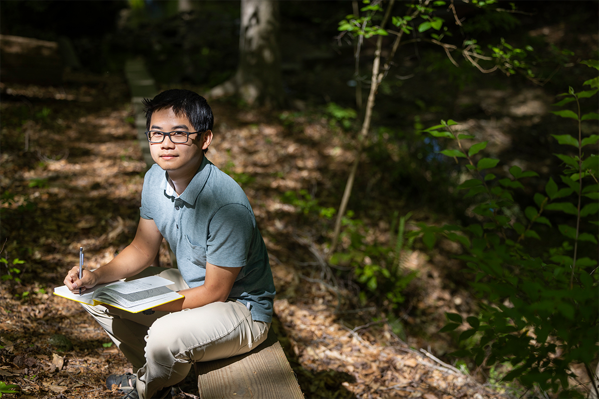 Chang studying in wooded area