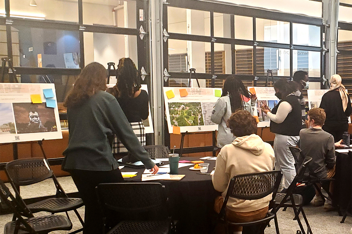 People in meeting room examining illustrations on easels.. 