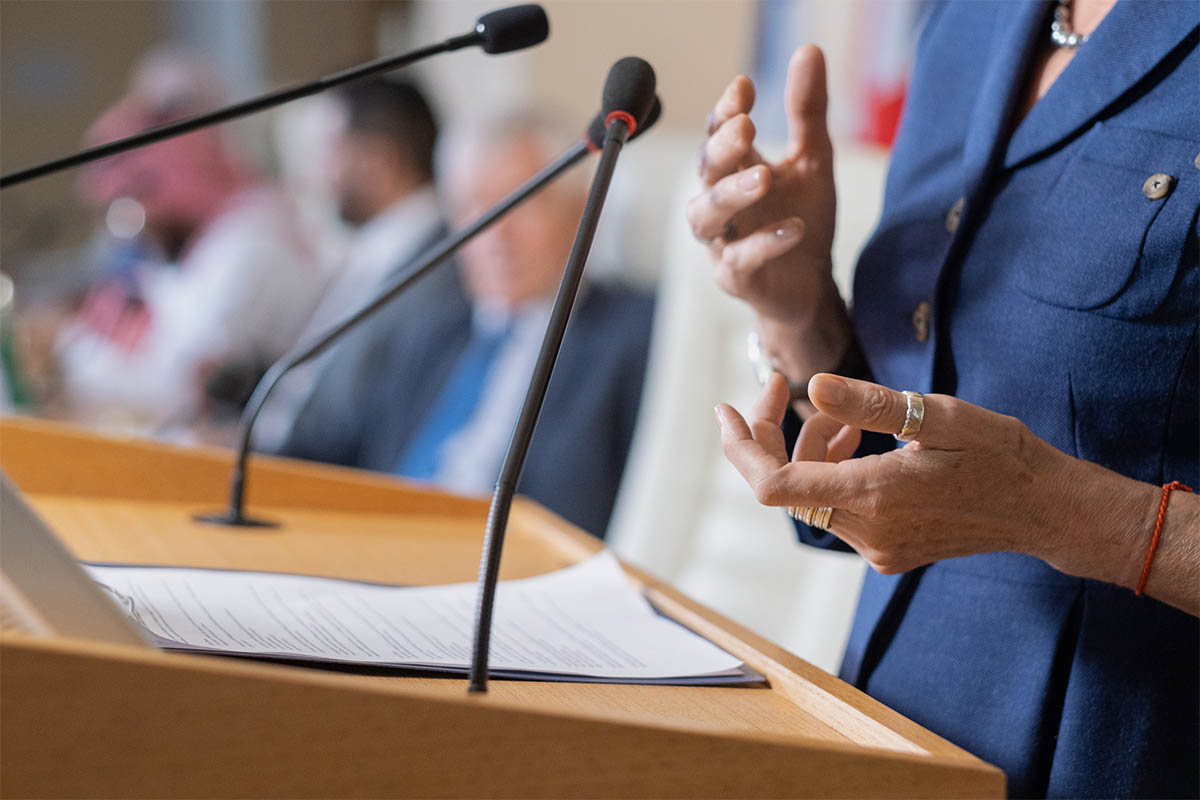 woman standing at podium speaking to crowd