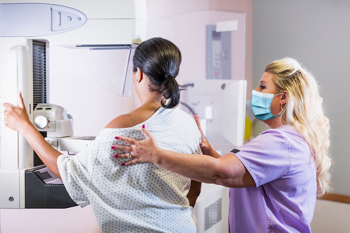 Physician directing patient in using mammogram machine