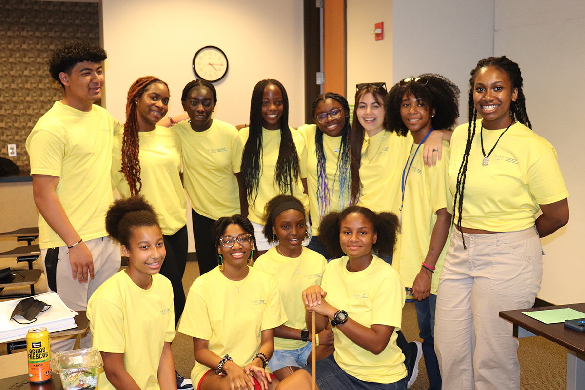 Group of smiling students in yellow tee shirts posing for photo.