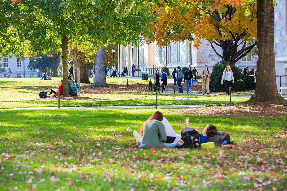 college students sitting in groups under trees on campus