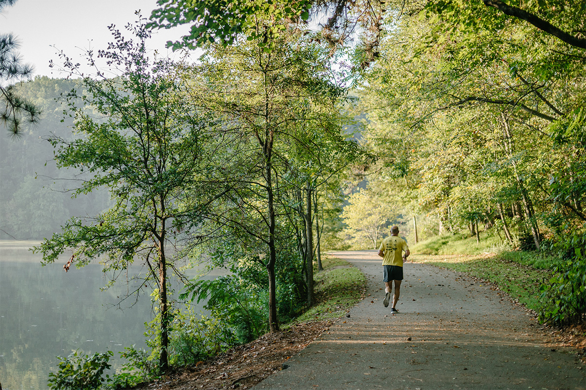 man jogging on path beside lake