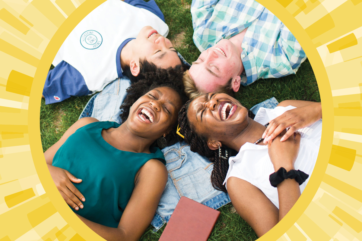 Photo illustration: smiling students, shown from above, lie on their backs on the grass with their heads together.