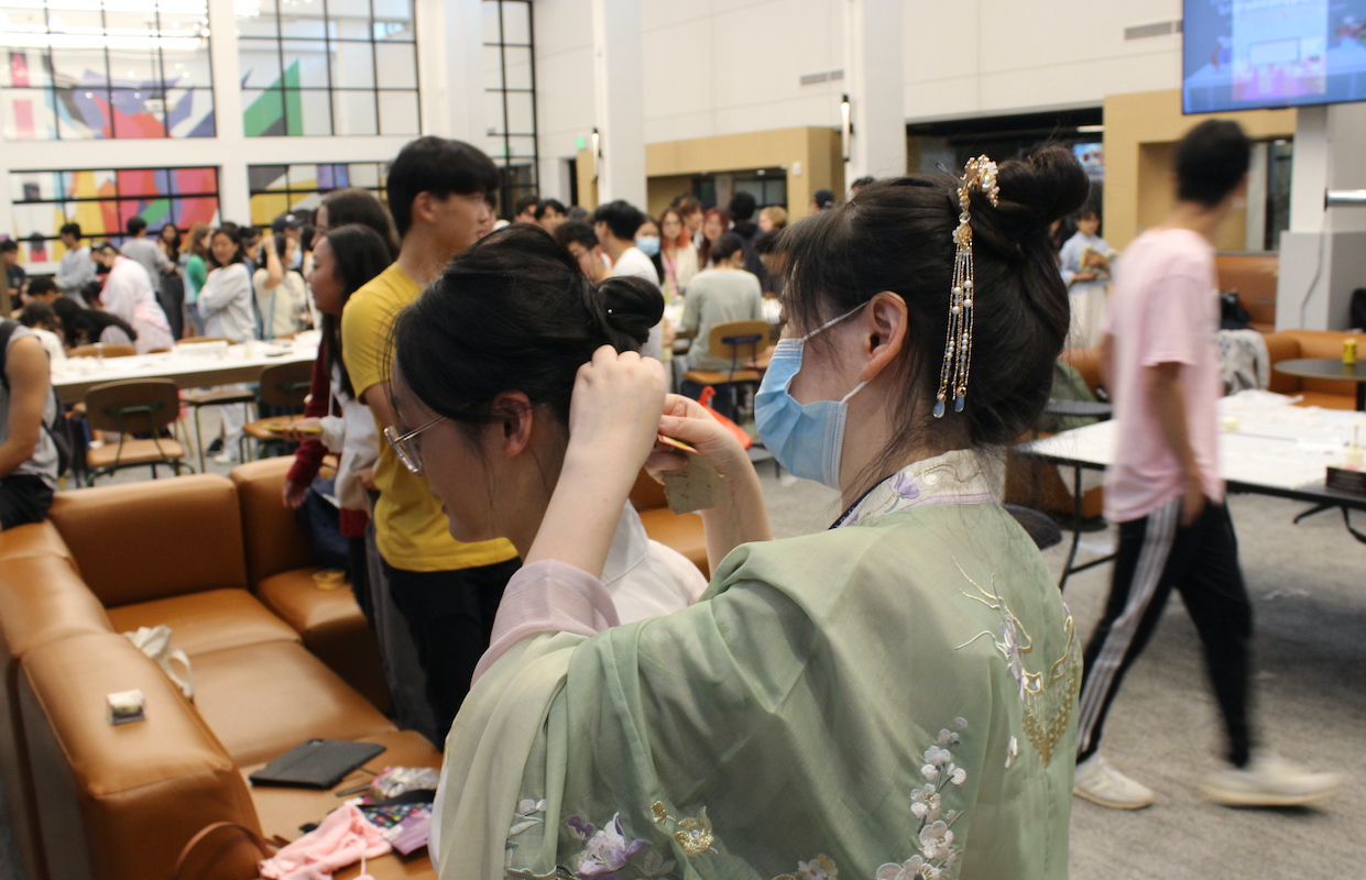 Student helping student with hair style for festival.
