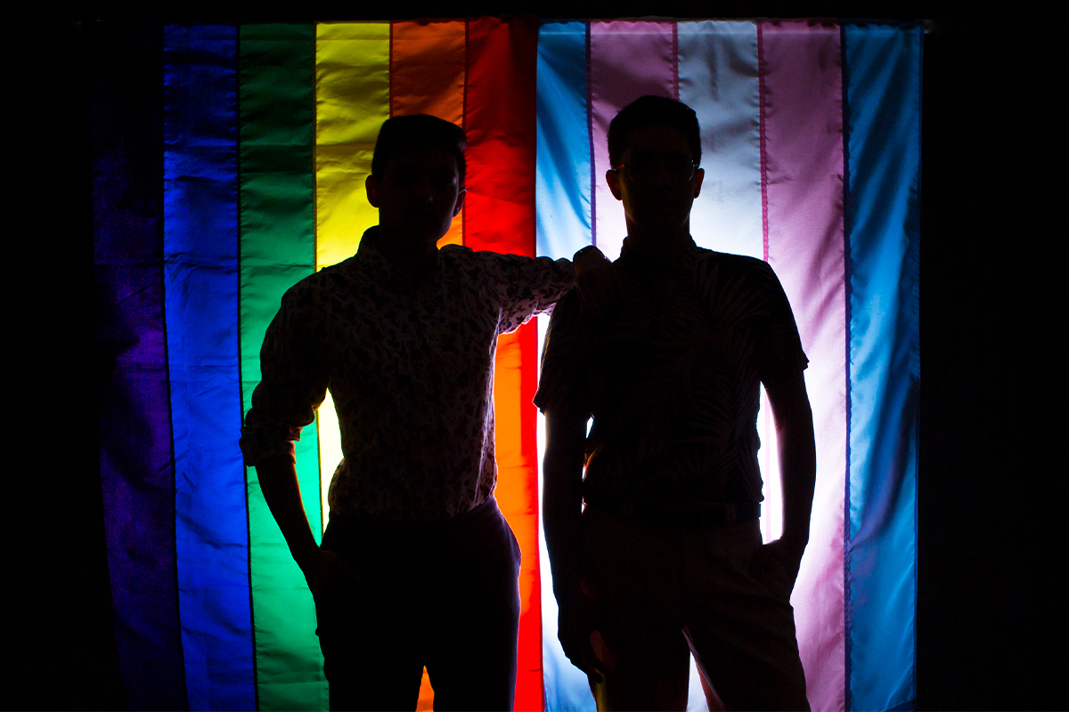 silhouettes of two people standing in front of diversity flag
