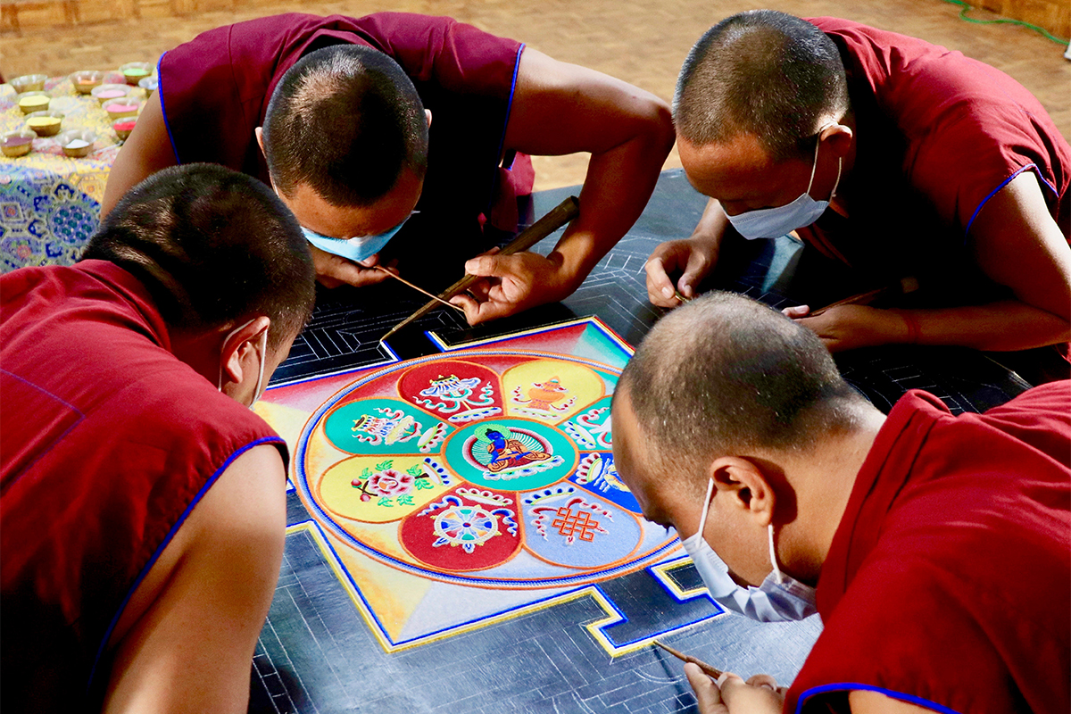 Four Tibetan monks working on sand sculpture
