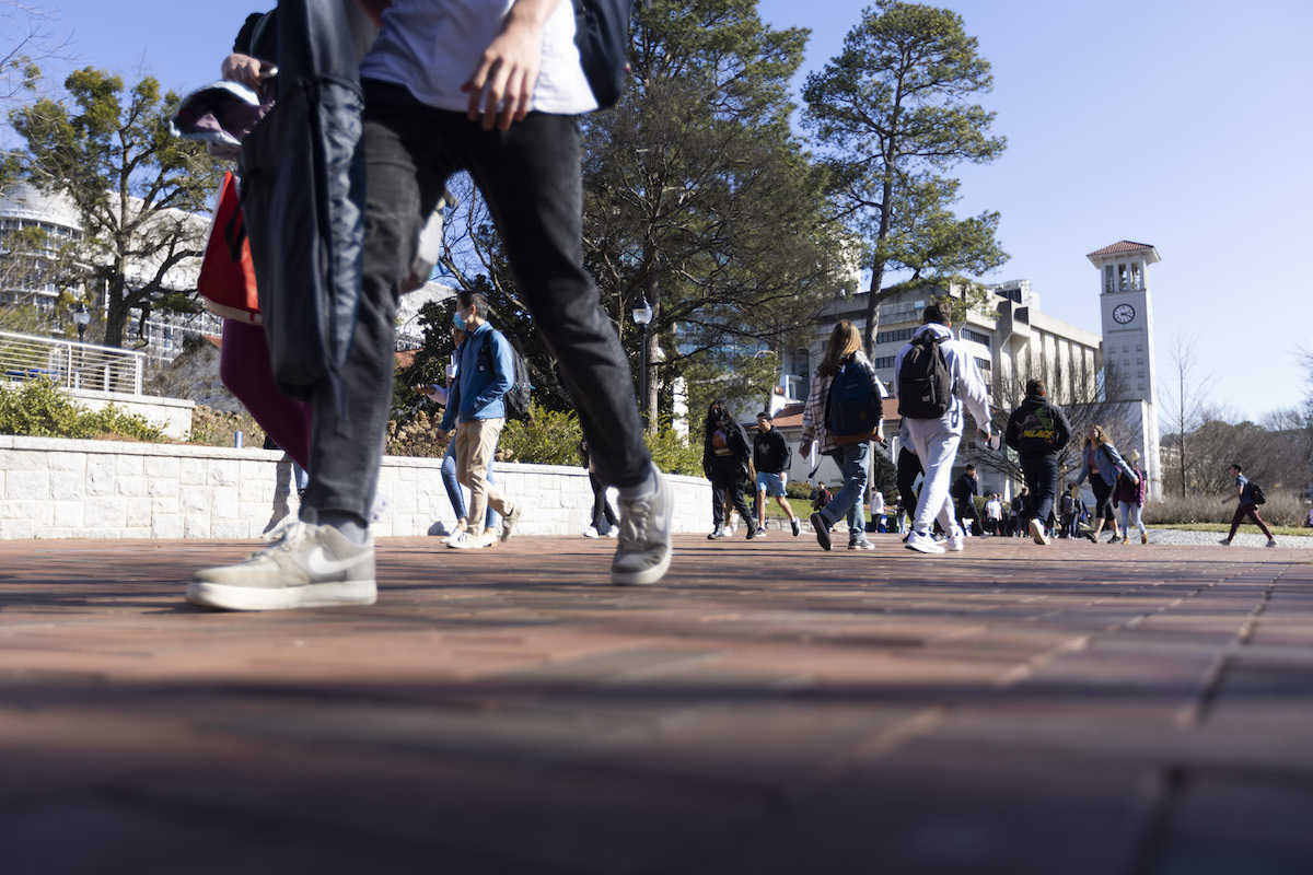 Photo: Low-angle of students walking on sidewalk outside west wall of Emory Student Center