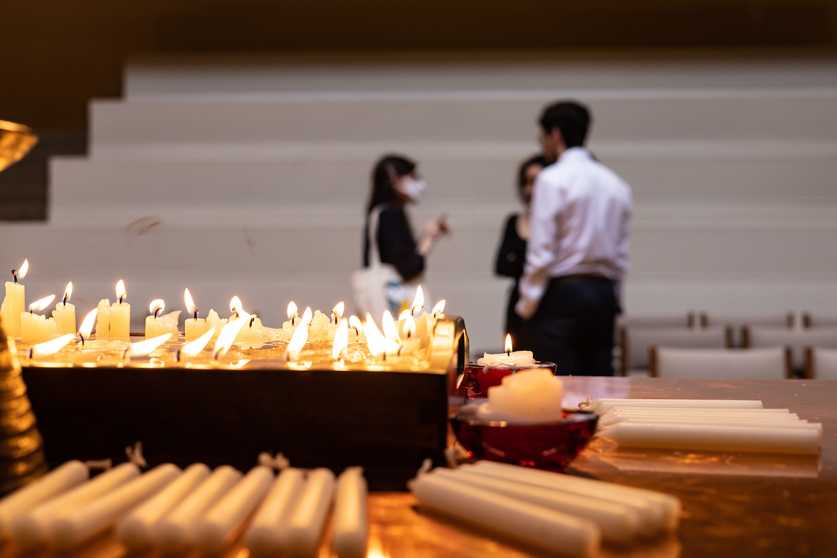 The lit candles burn down as attendees chat after the event