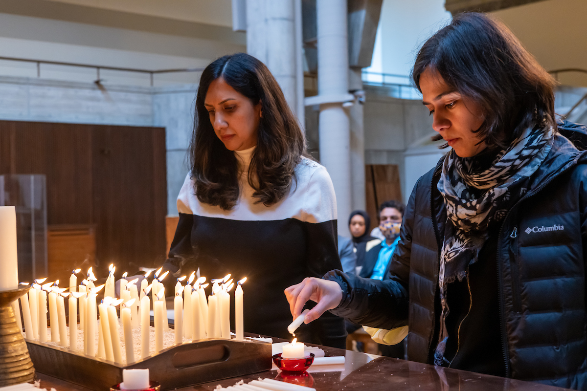 Two attendees light candles in honor of the victims