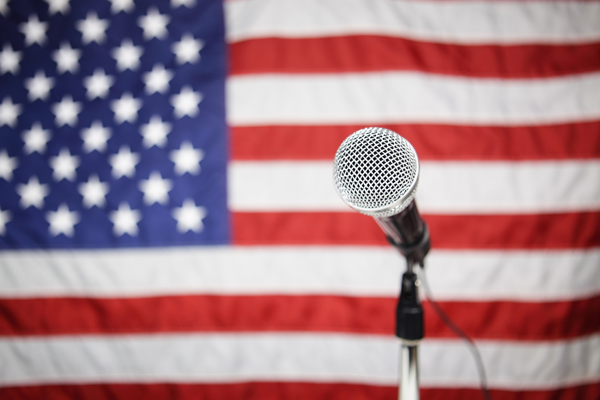 Image of a microphone in front of the American flag