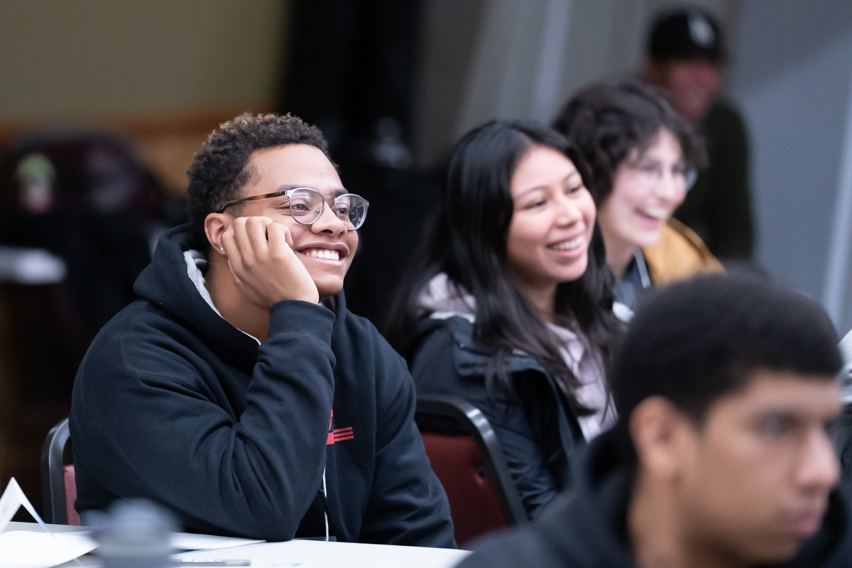 Photo of students listening to speaker and smiling