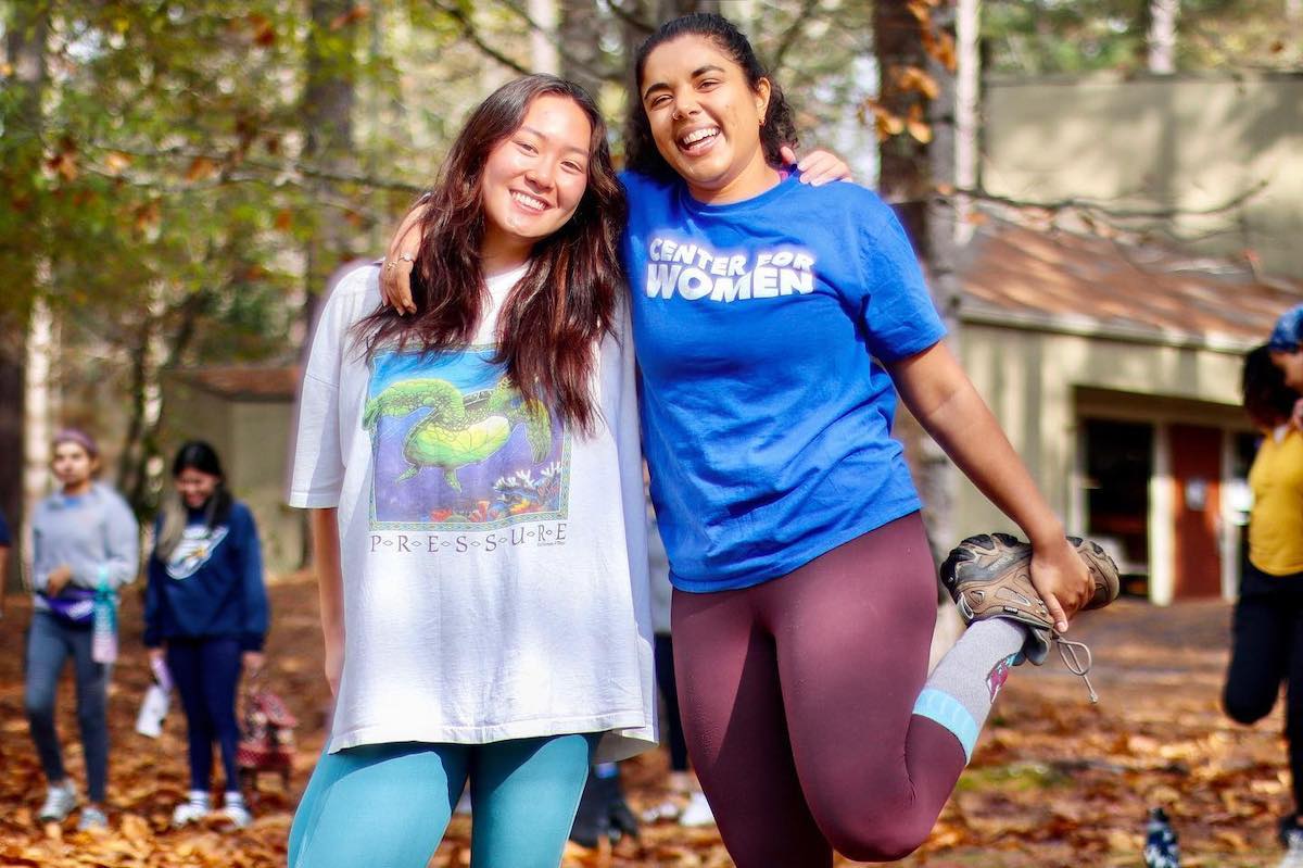 Photo: Full shot of two women students smilining at camera on autumn day on the Quad