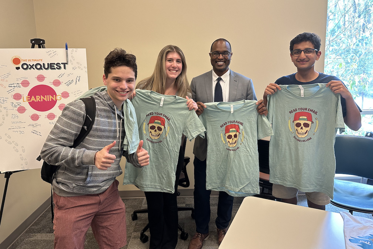 Photo: Oxford's Dean Carter and three students holding OxQuest tee shirts