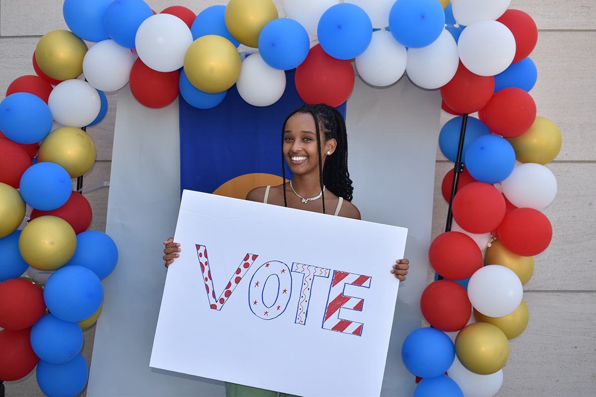 Elaini Asamere holding 'vote' poster