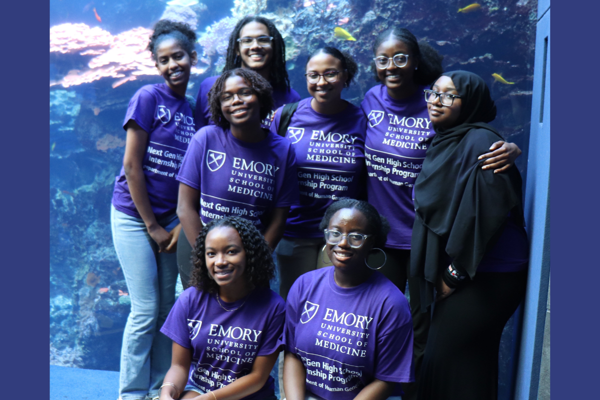 Group of 8 students in purple Emory University School of Medicine t-shirts, standing in front of a tank at the Georgia Aquarium