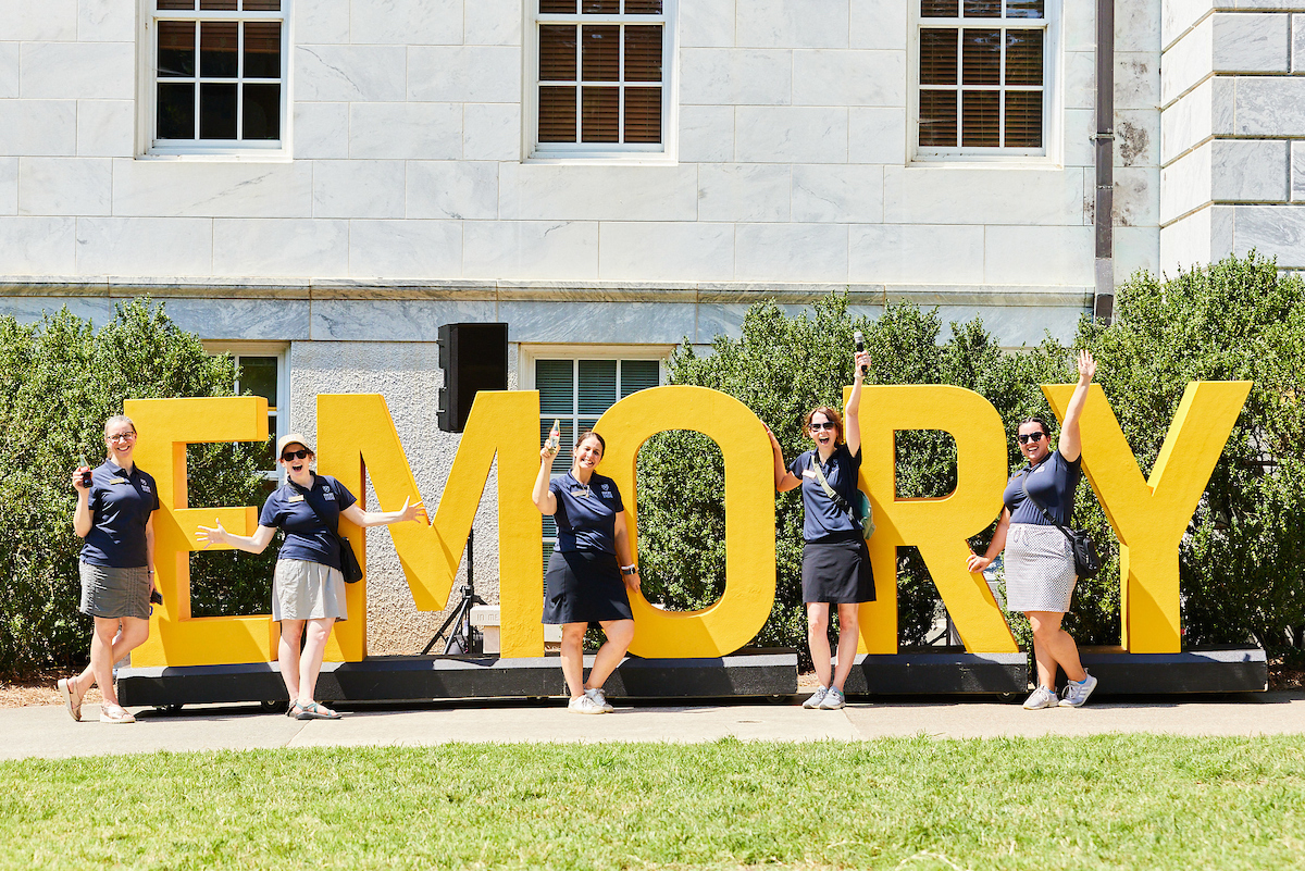 students in front of emory sign