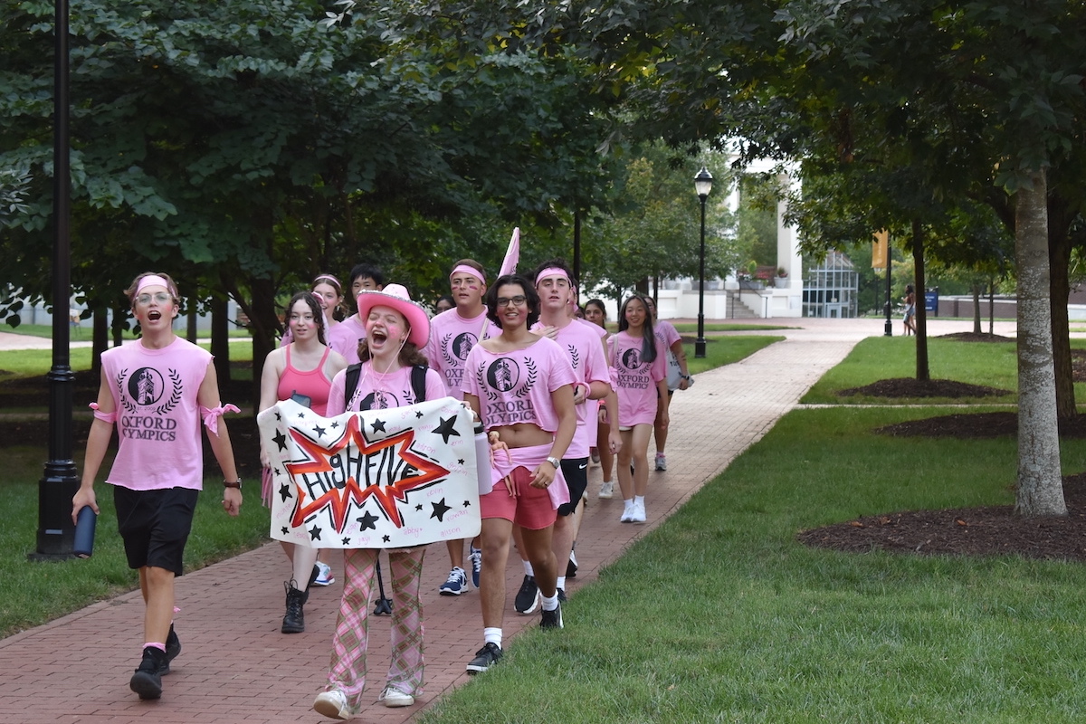 Photo: Group of Oxford students in event tee-shirts marching with sign across campus