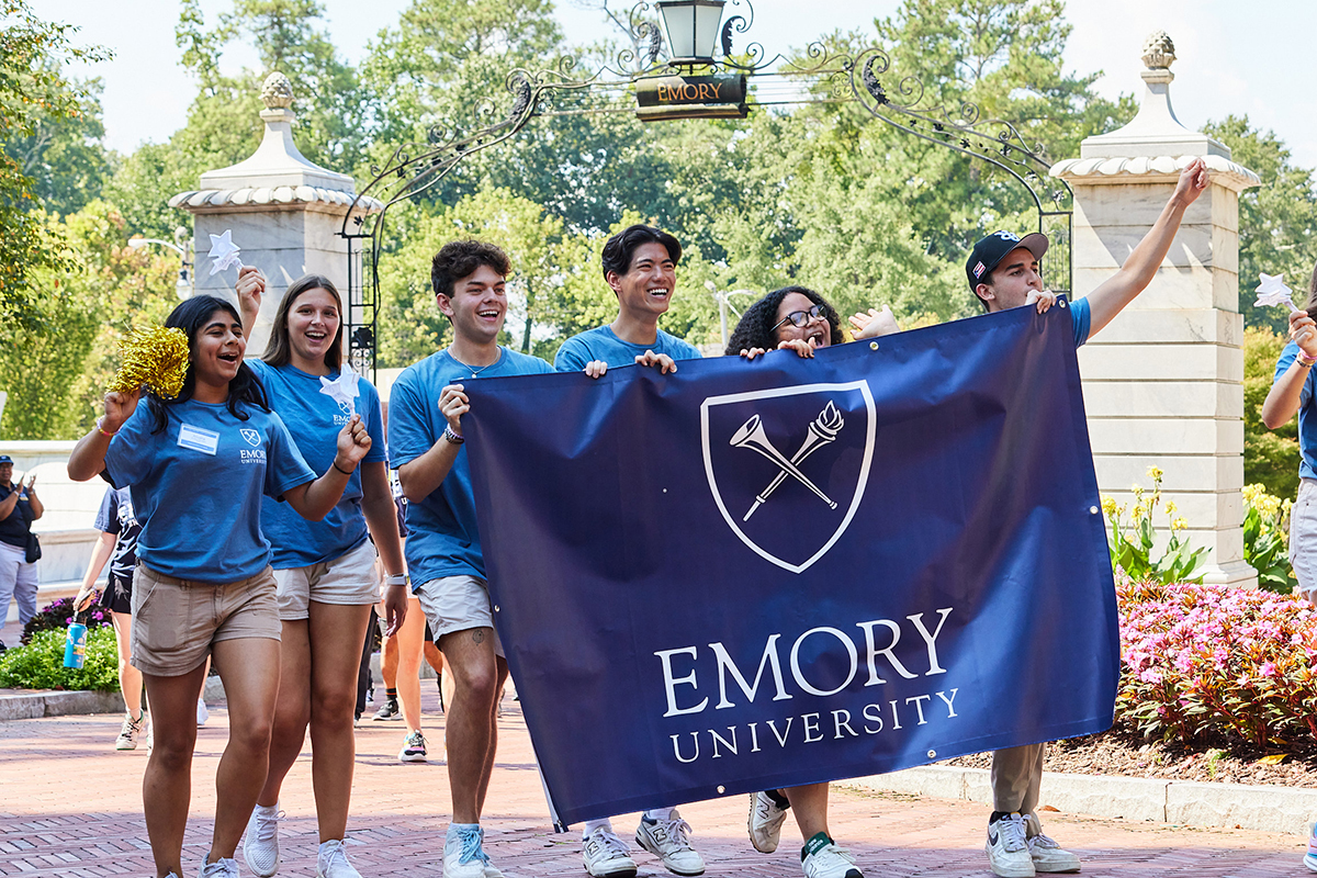 students walking through campus gate with Emory banner
