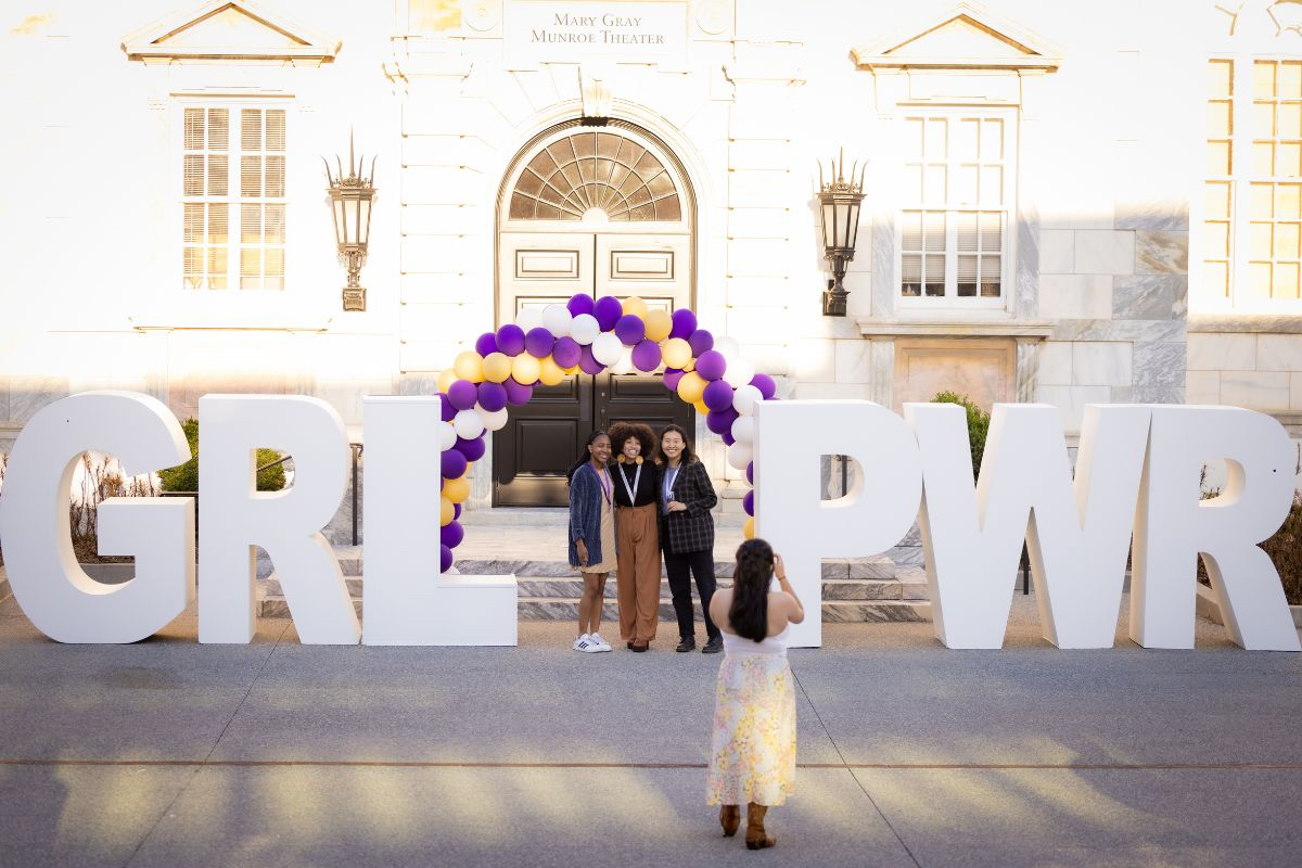 Two women in front of GRL PWR letters and balloons