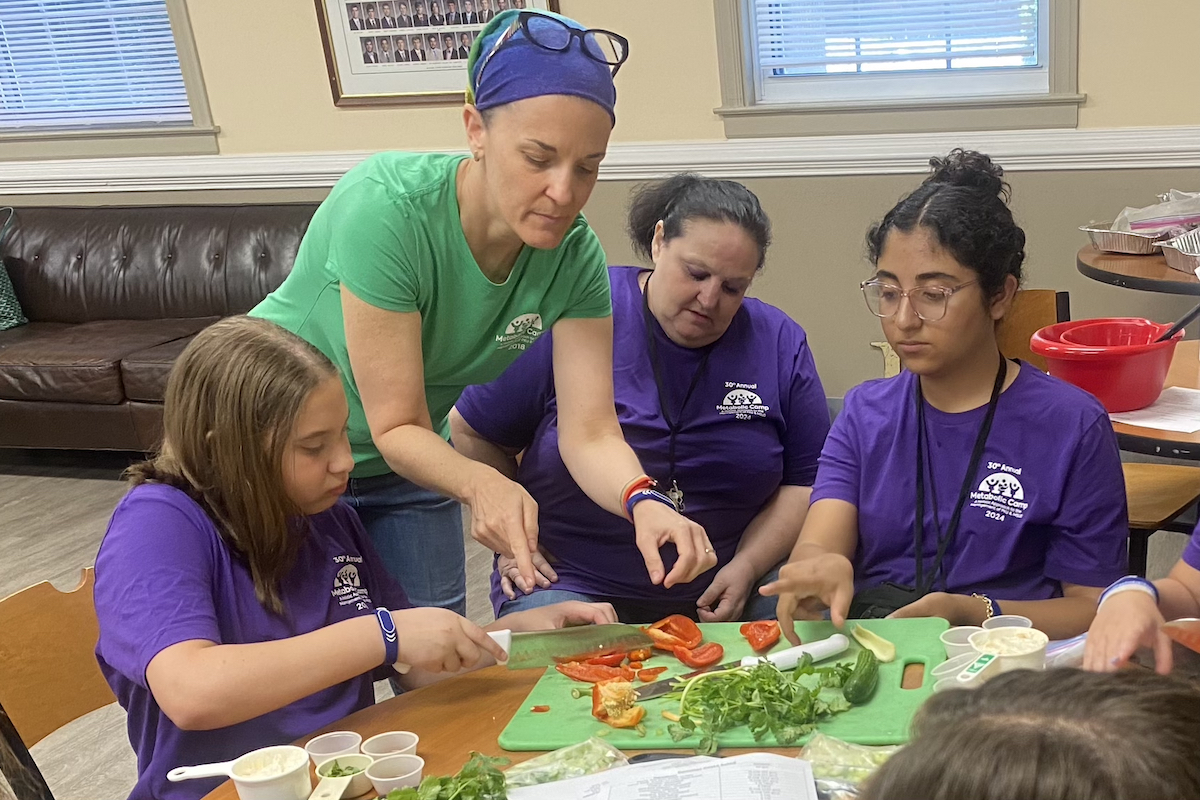 Metabolic dietitian and chef Kristen Narlow (with headband) instructs campers on a special low-protein recipe for pasta salad.