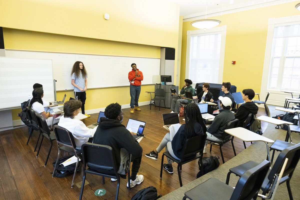 photograph of students in a classroom sitting in a circle around two presenters