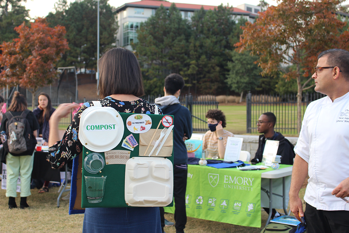 Young woman wearing a backpack that says Compost at an Emory Farmers Market event