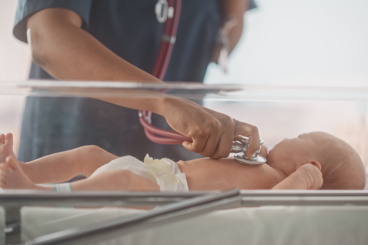 Health care worker checking infant with stethoscope