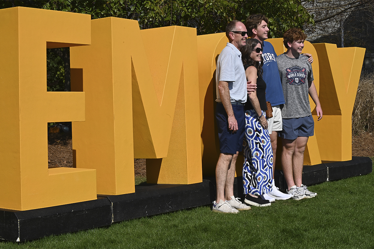 family smiles in front of Emory letter sign