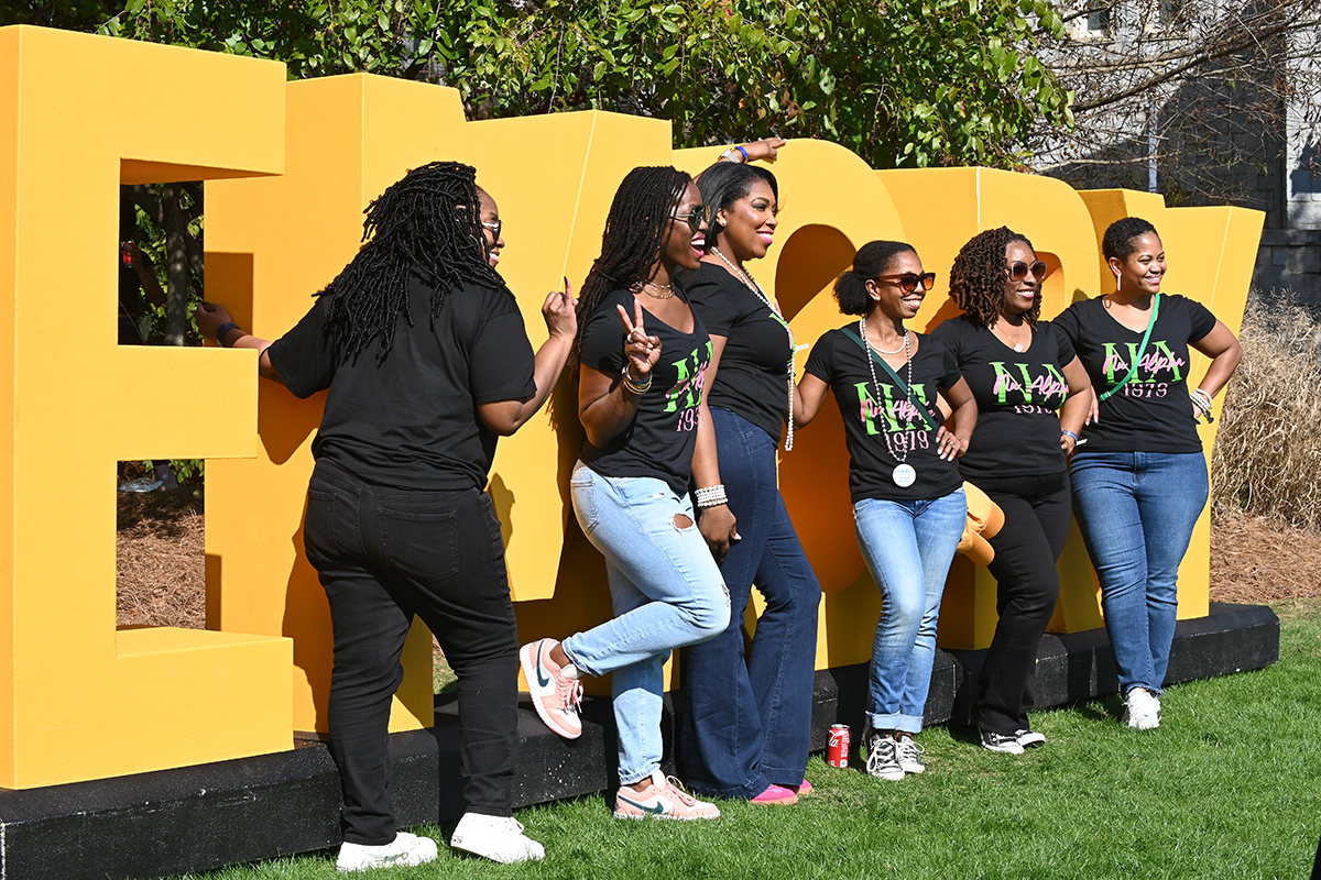 a group poses in front of large Emory letters