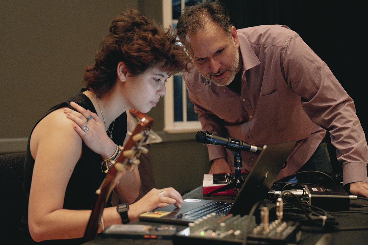 college student and professor look at a laptop and music soundboard