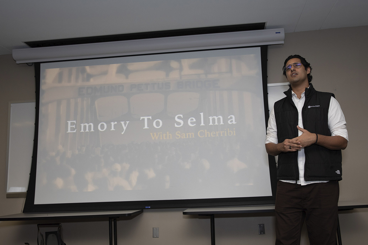 male college student speaking in front of a presentation screen