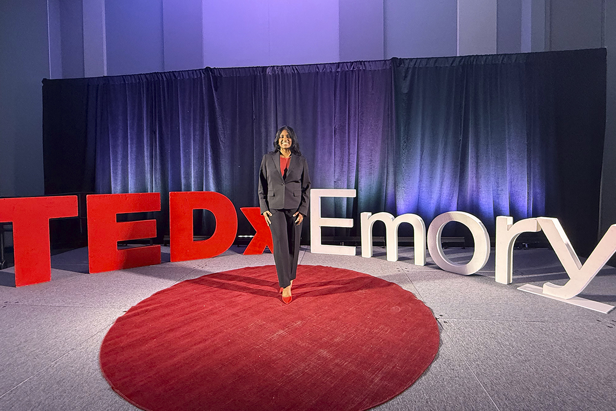 Woman stands in front of large Tedx Emory letters