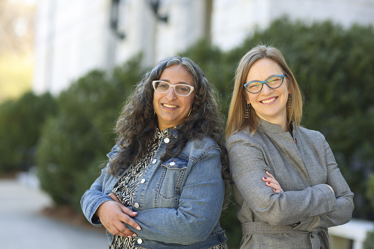 Emory University professors Sameena Mulla and Christina E. Crawford standing back to back outdoors