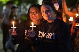 two students holding candles and smiling