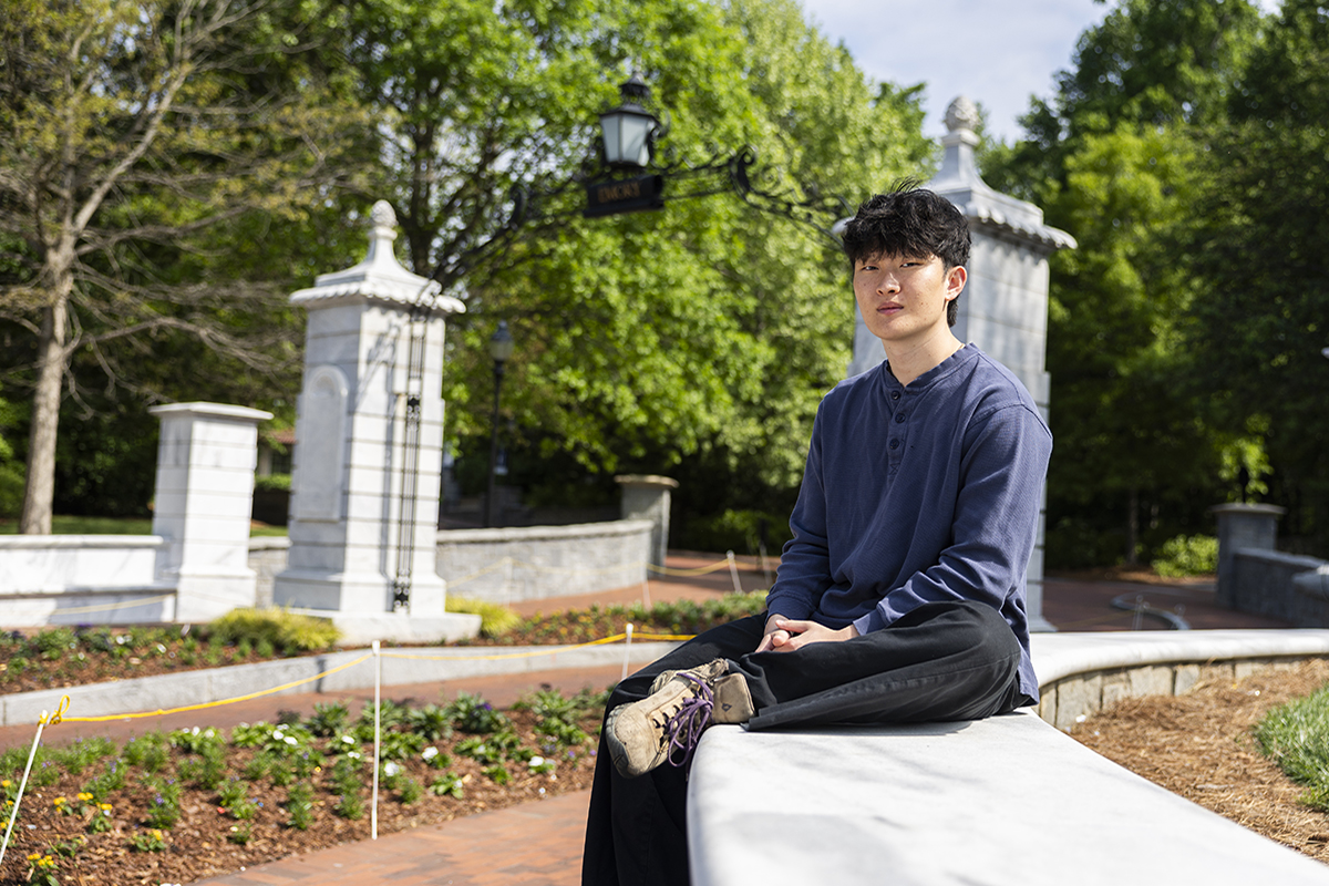 Benjamin Cho sits on wall in front of Emory University entrance