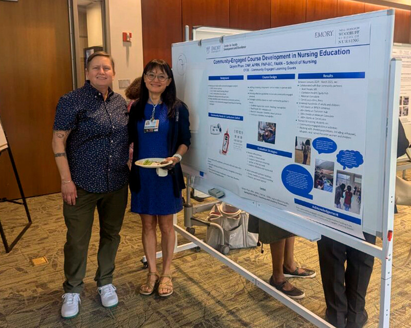Two faculty members pose in front of poster presentation at Faculty Showcase