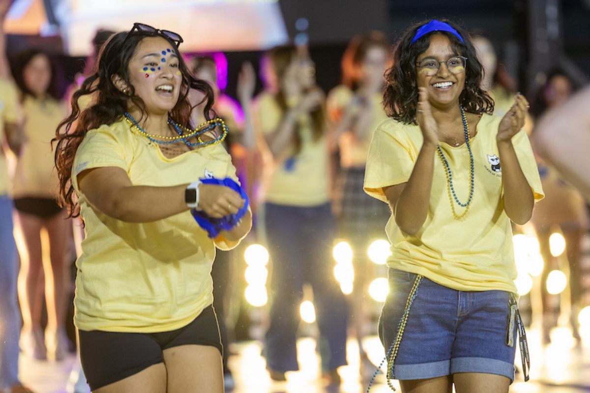 group of students in yellow t-shirts dancing during Songfest 