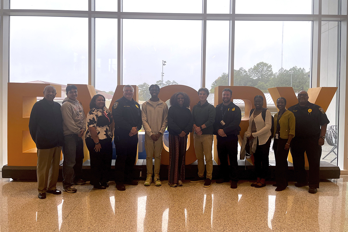 group of people standing in front of large letters spelling Emory