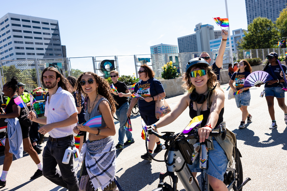 Parade goers, including one who is biking, crossing an overpass