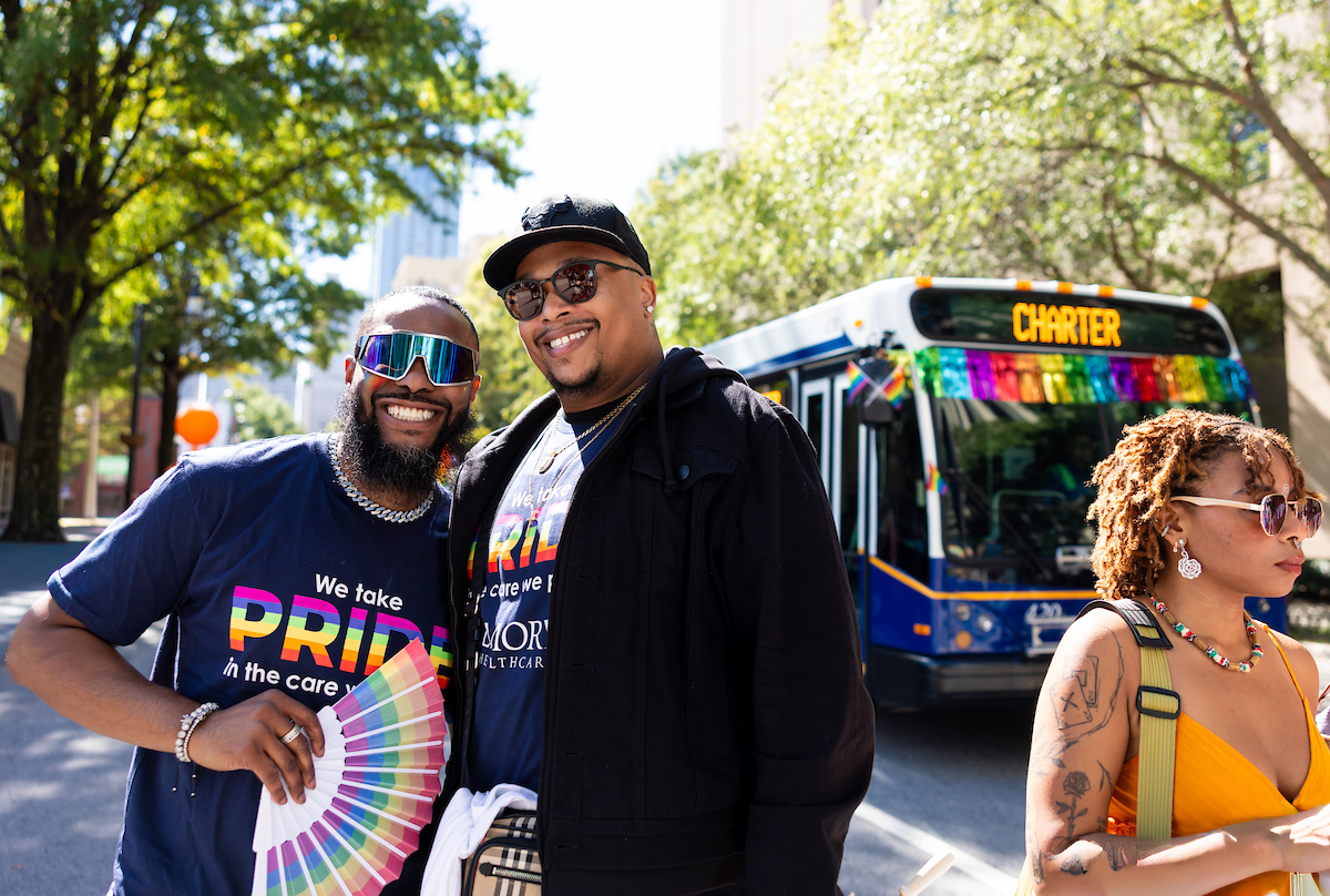 Two men in pride shirts smiling