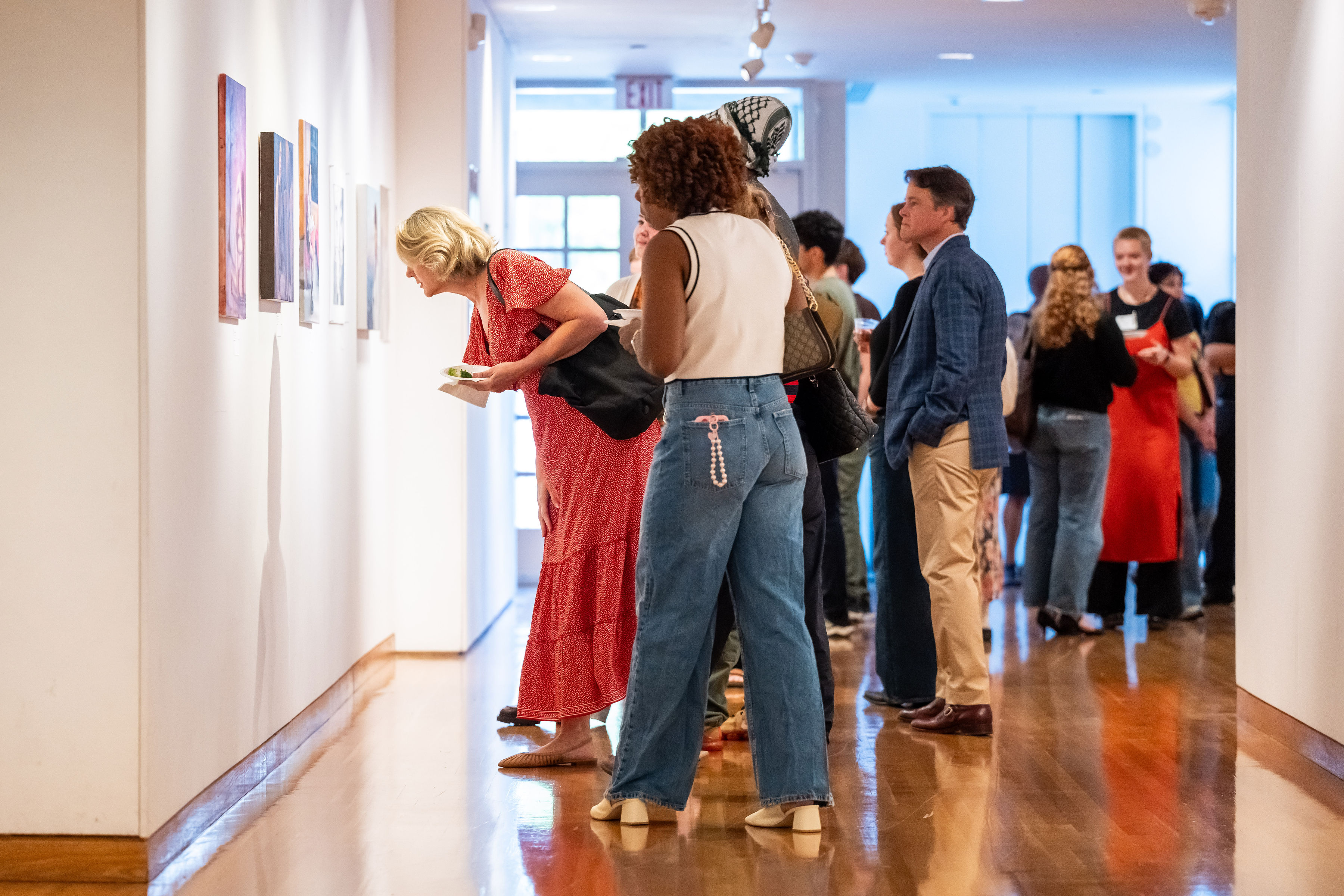 Folks inspecting the displayed works