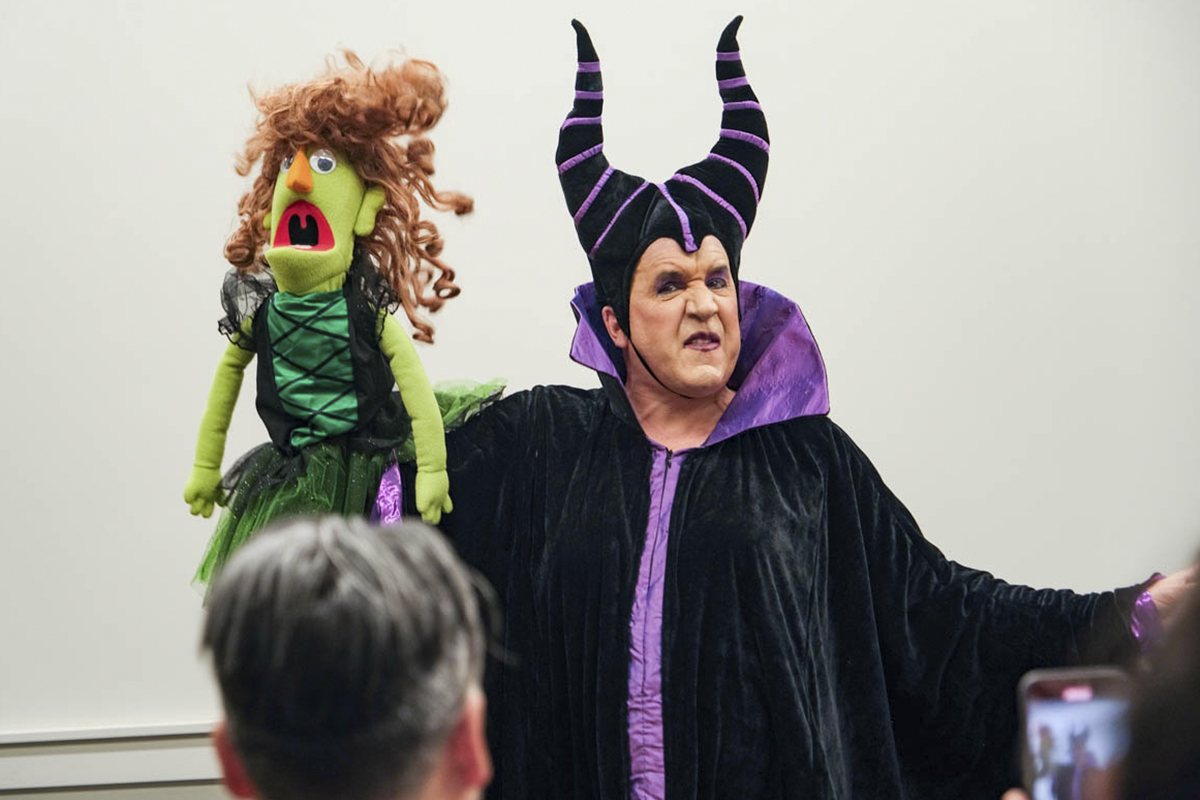 performer dressed in witch costume and holding large puppet