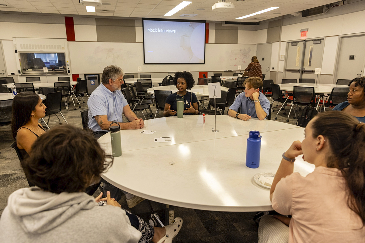 college students and an adult sitting around a table talking