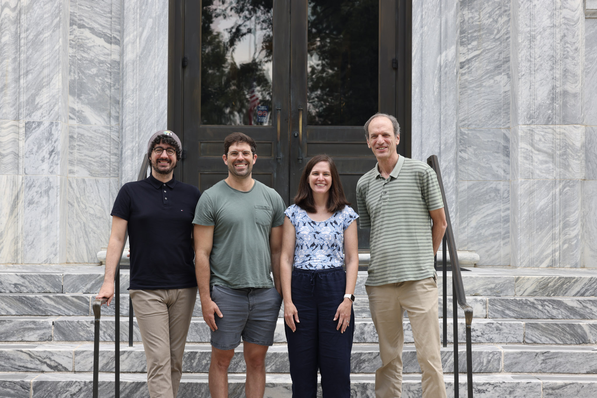 four folks stand together on steps