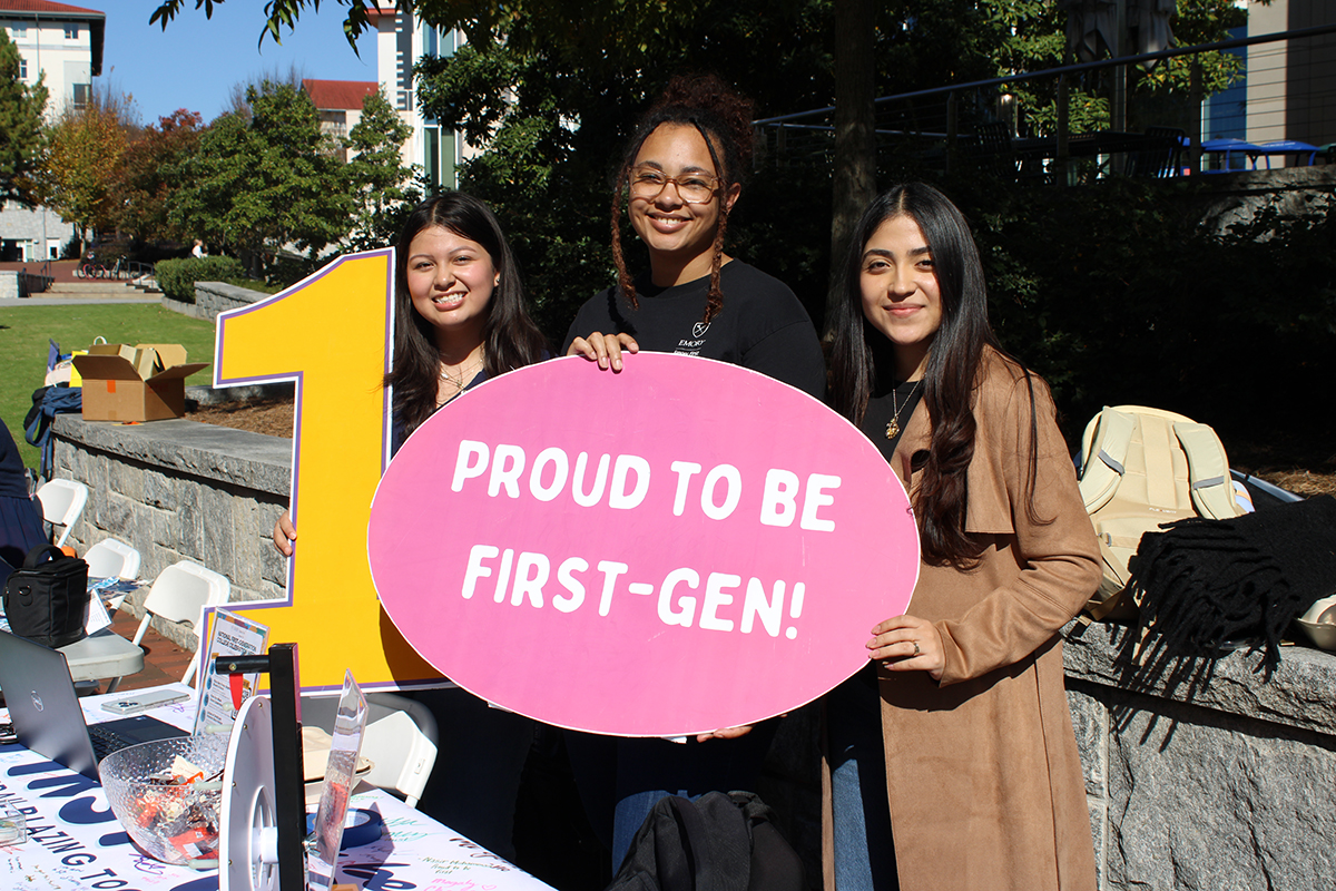 students holding up a proud to be first-gen sign