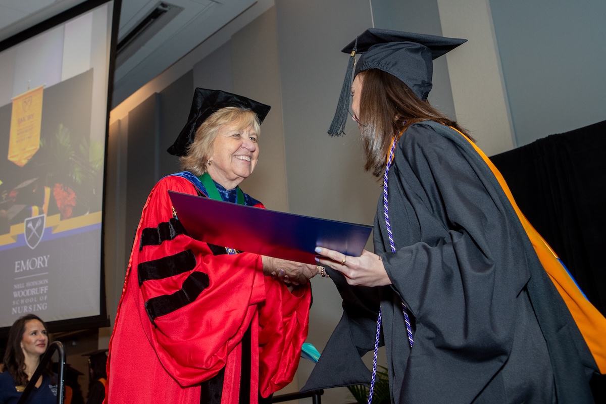 Dean Linda McCauley greets a graduate on stage at commencement